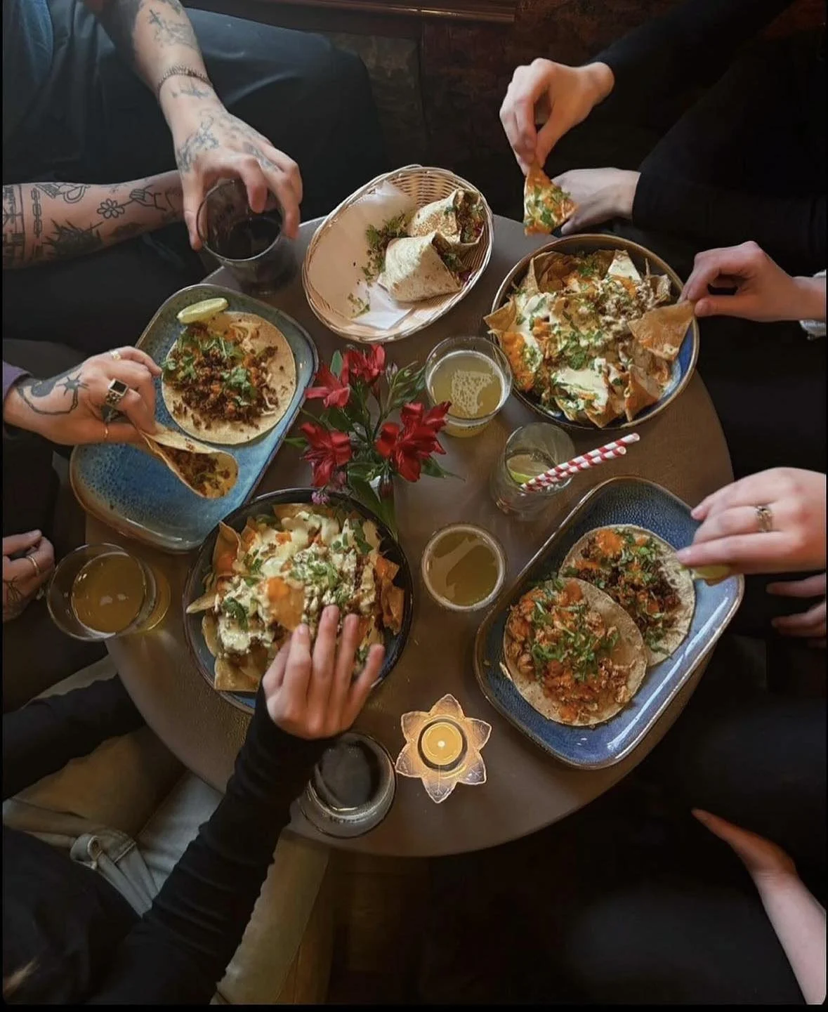 Matarborð séð ofan frá þar sem fimm manns borða tacos og fá sér drykki.